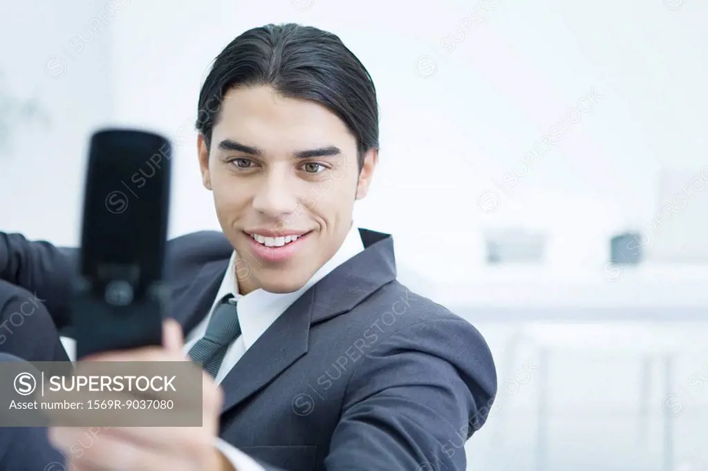 Young businessman using cell phone to take picture of himself, smiling