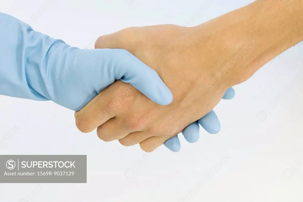 Cropped view of handshake, one hand wearing rubber glove, close-up