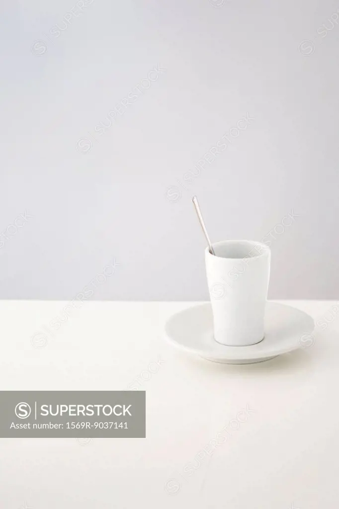 Cup resting on saucer, spoon in cup