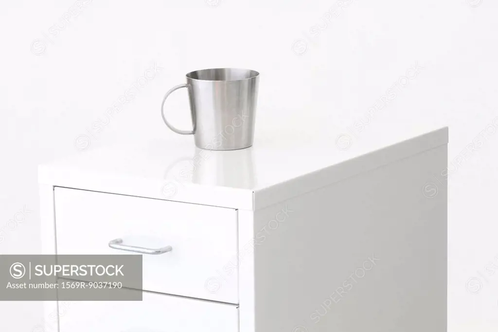 Metal cup on top of a filing cabinet