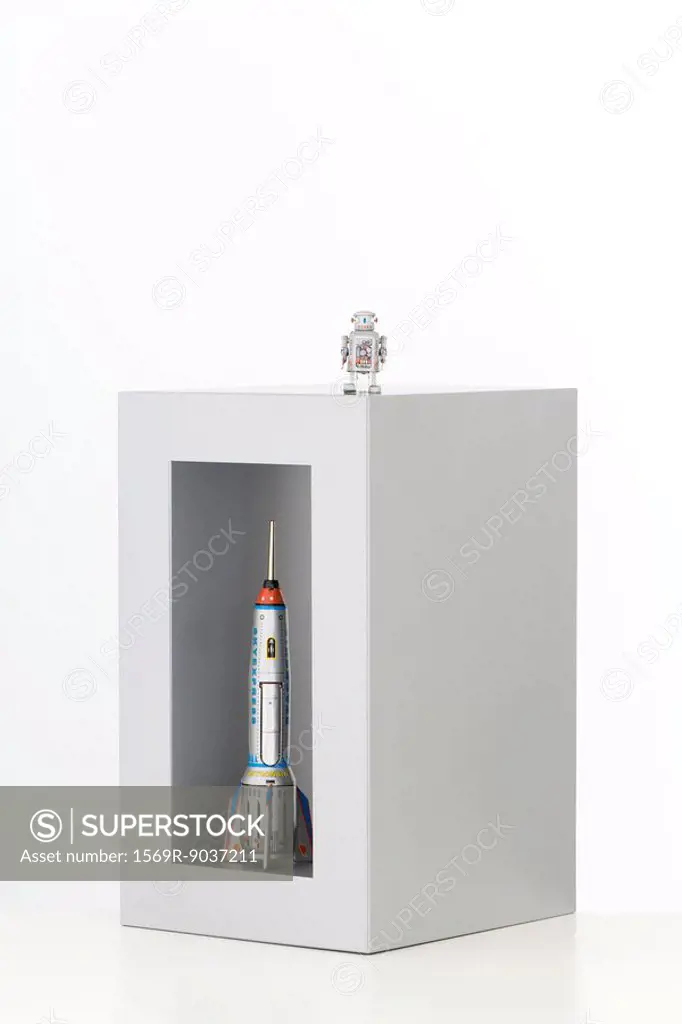 Toy robot standing on top of a box with a toy rocket standing up in it