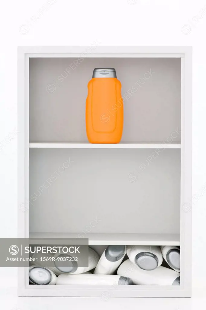Bottles in medicine cabinet, many white bottles in a mess on the bottom, one orange bottle standing on top shelf