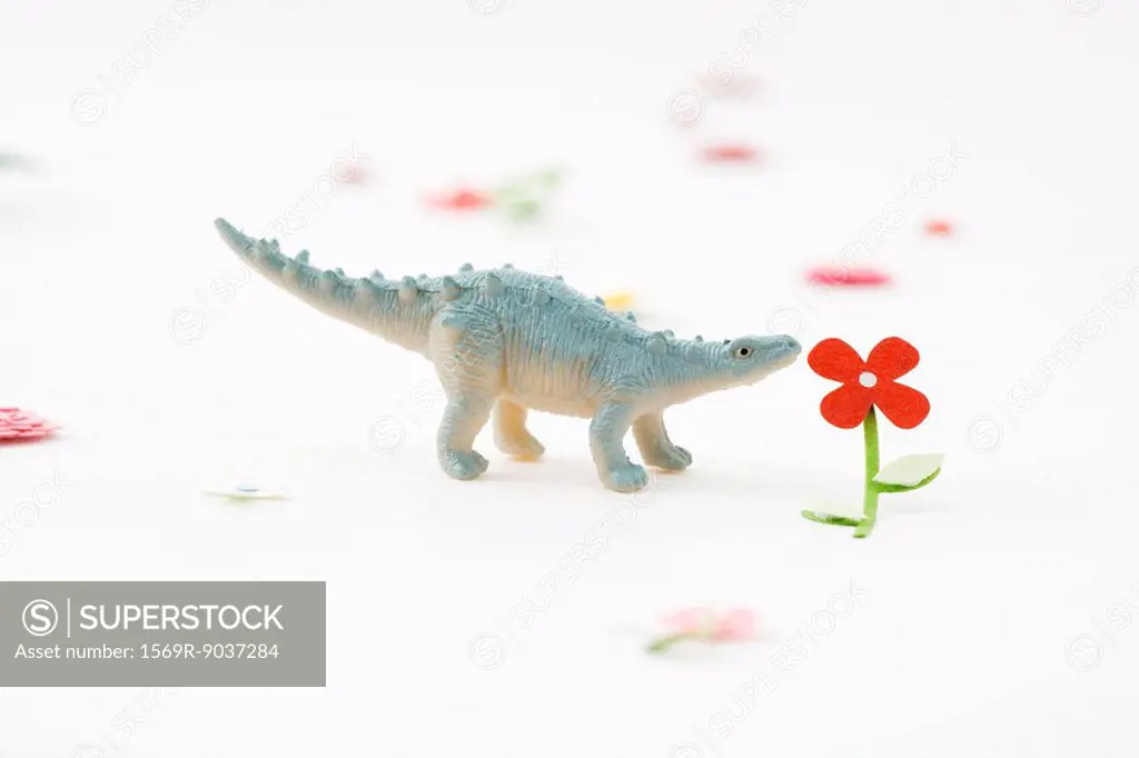 Toy dinosaur smelling artificial flower