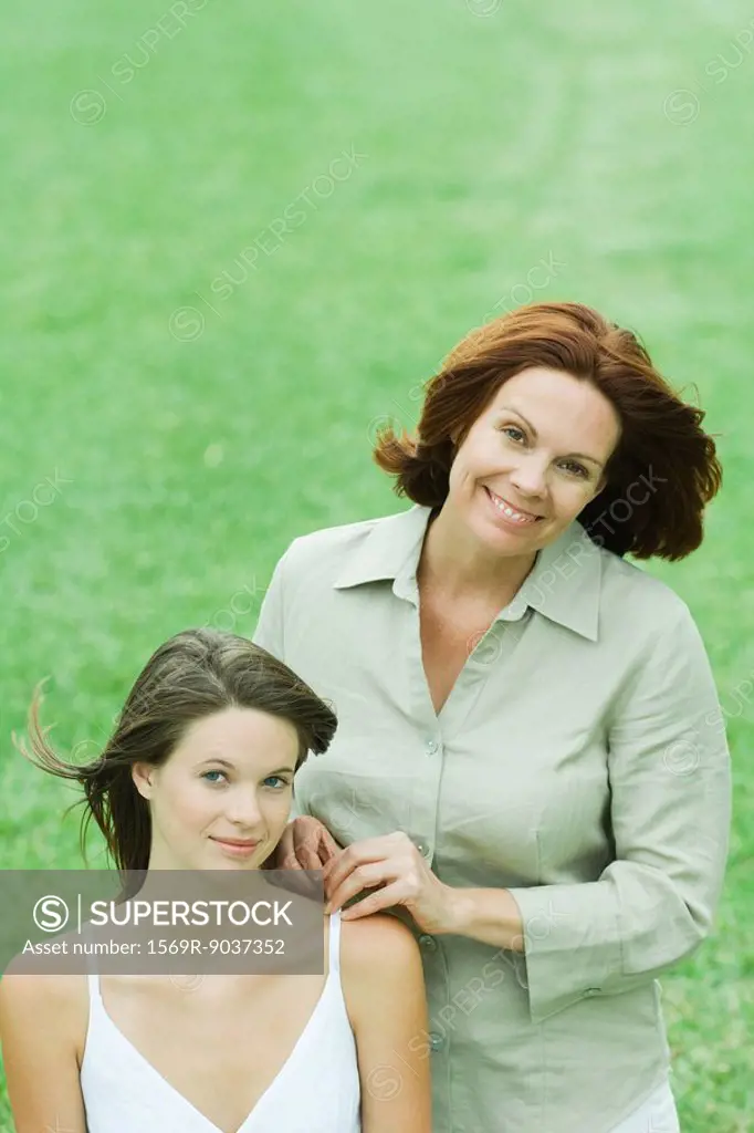 Mother with teenage daughter, both looking at camera smiling, portrait