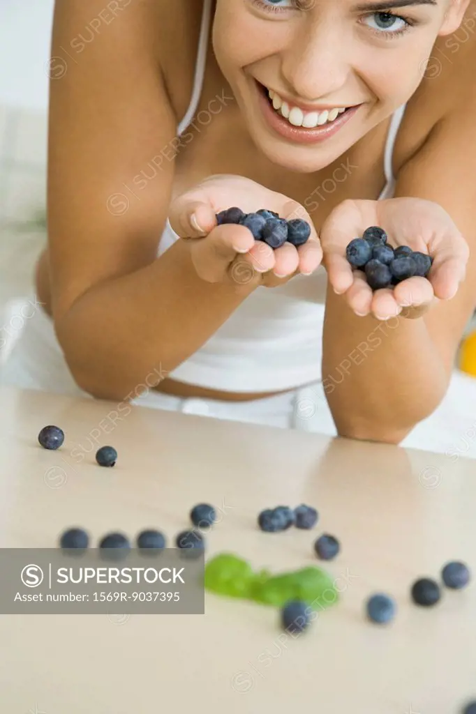 Woman with hands full of blueberries, smiling