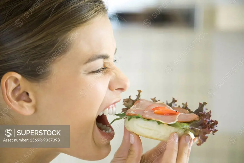 Woman eating open faced ham sandwich, close-up