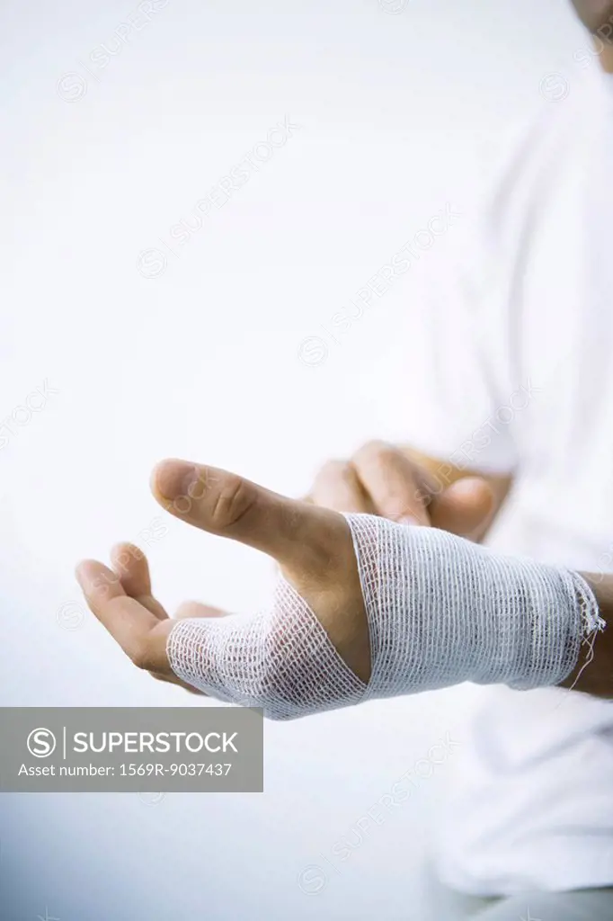Man wrapping hand with gauze, cropped view