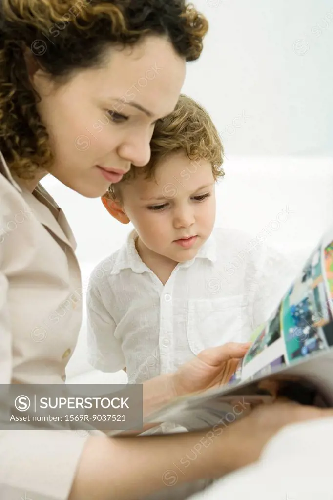Mother and toddler son reading comic book together