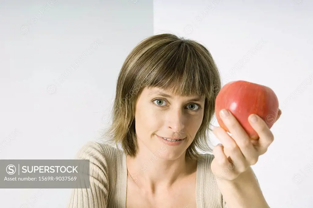 Woman holding red apple, smiling at camera