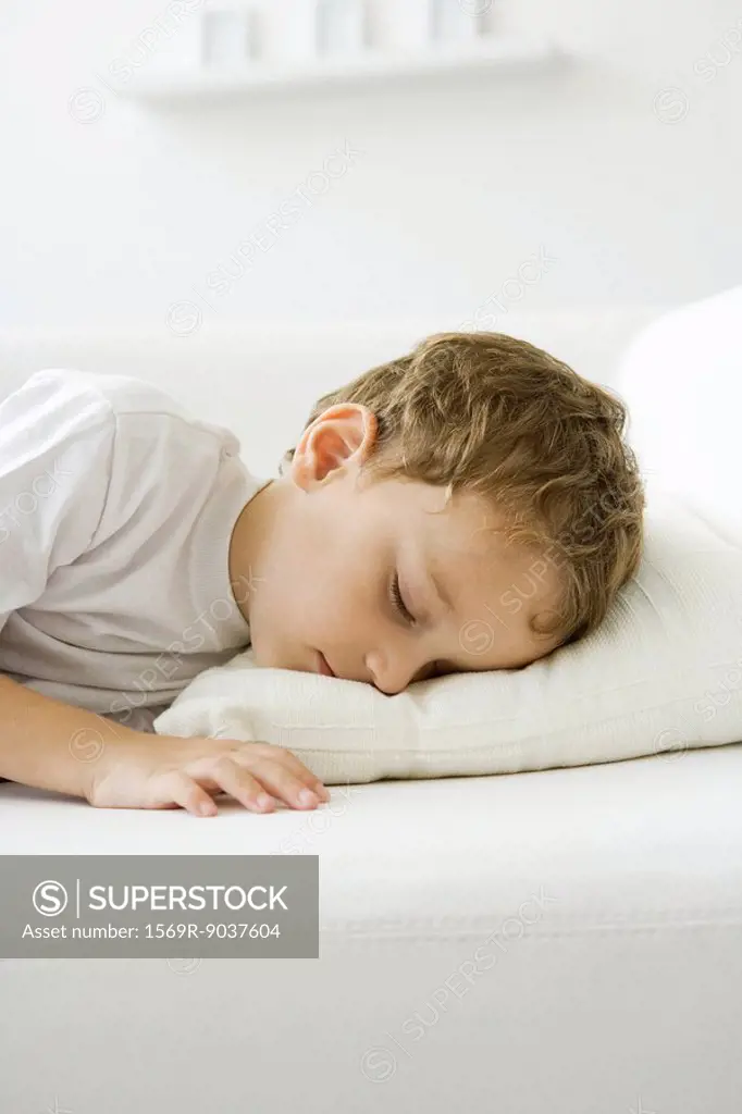 Little boy napping on bed, eyes closed
