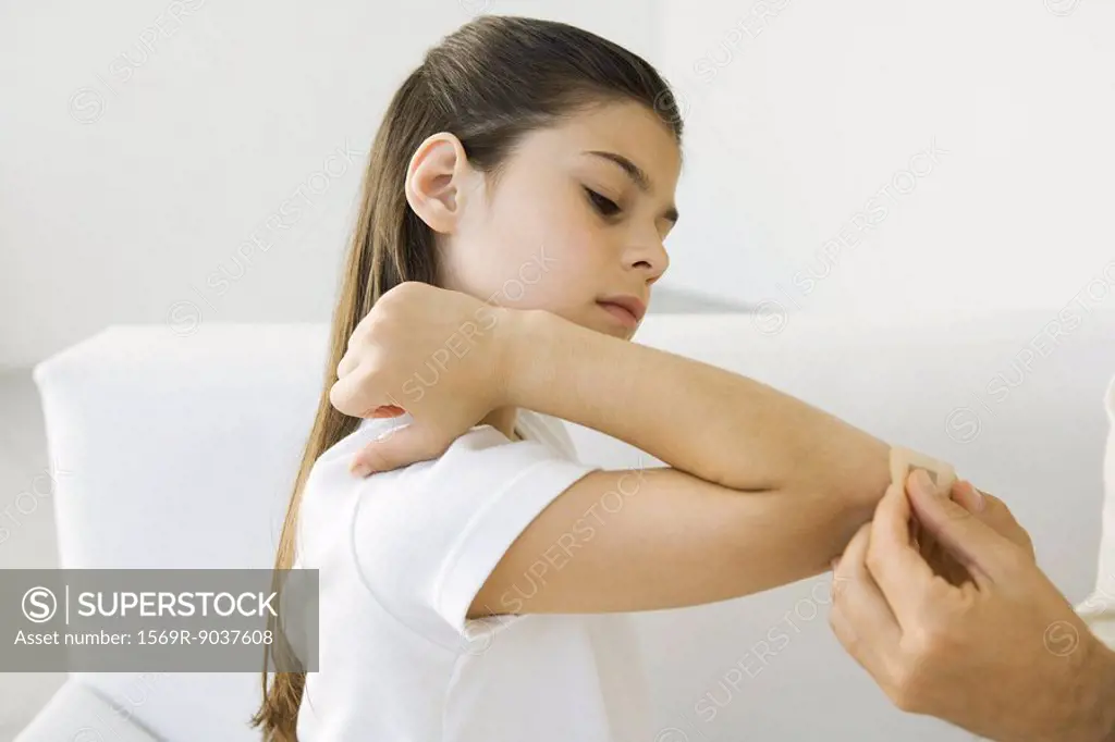 Man putting adhesive bandage on girl´s elbow, cropped view