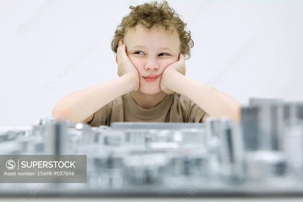 Little boy sitting with computer motherboard, holding head, looking away