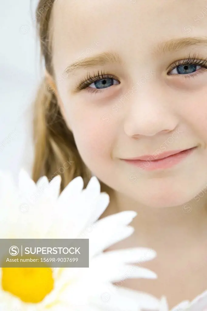 Little girl holding daisy, smiling, portrait
