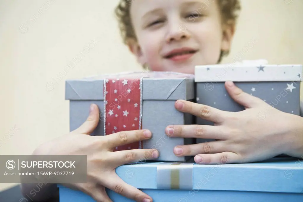 Young boy holding armful of gifts, smiling