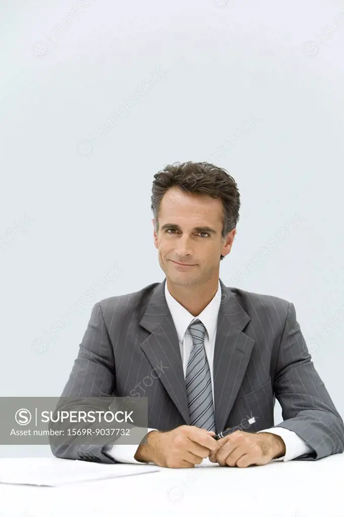Businessman seated at desk, smiling at camera