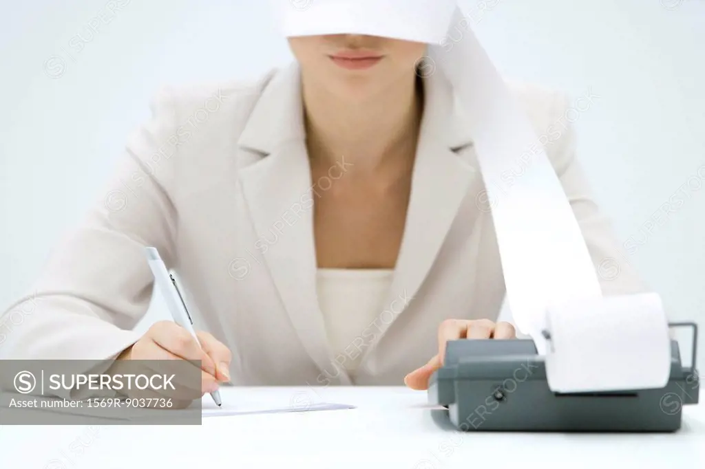 Accountant using adding machine, printout wrapped around her face like blindfold, cropped view