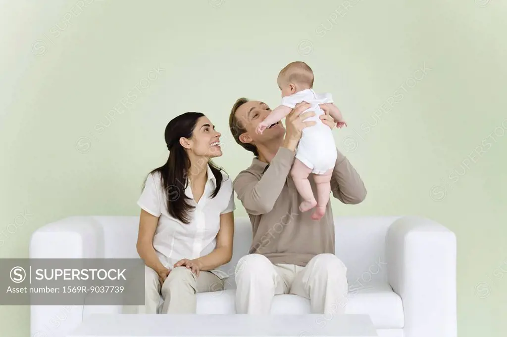 Parents sitting together on sofa, man holding baby