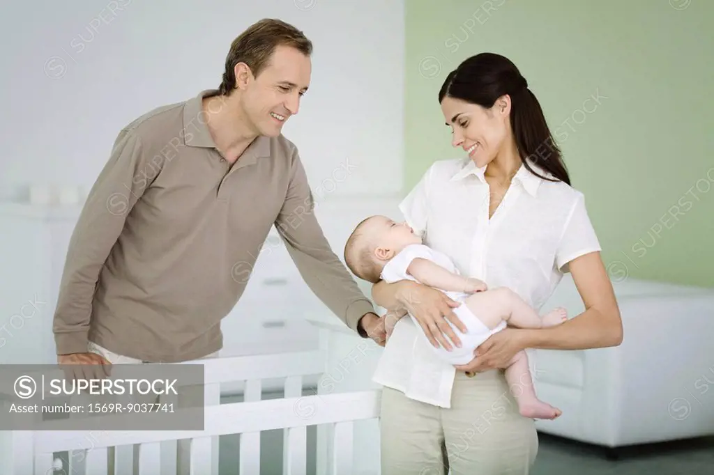 Parents standing in nursery, woman holding sleeping baby
