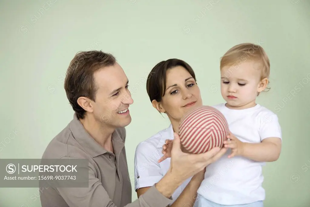 Parents giving toddler a ball