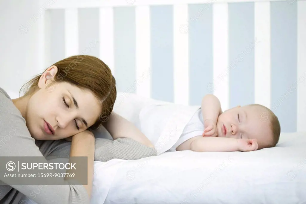 Mother resting head beside sleeping infant, eyes closed