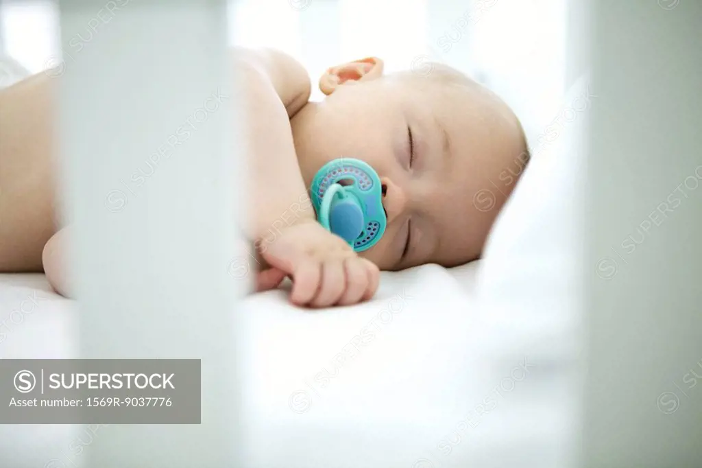 Baby sleeping in crib, pacifier in mouth