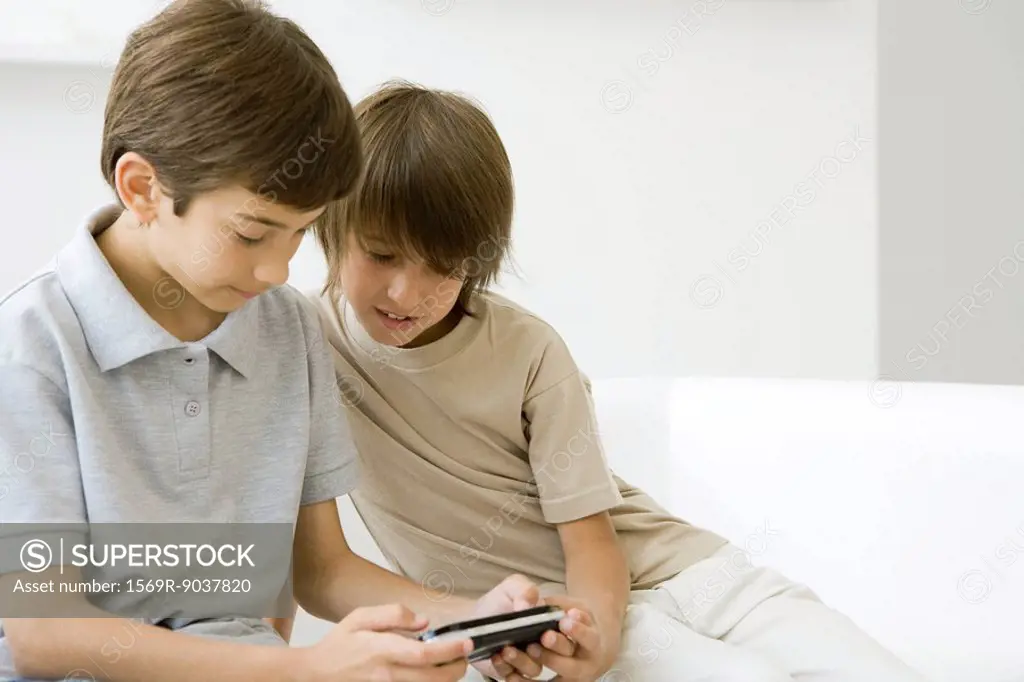 Two boys playing handheld video game together