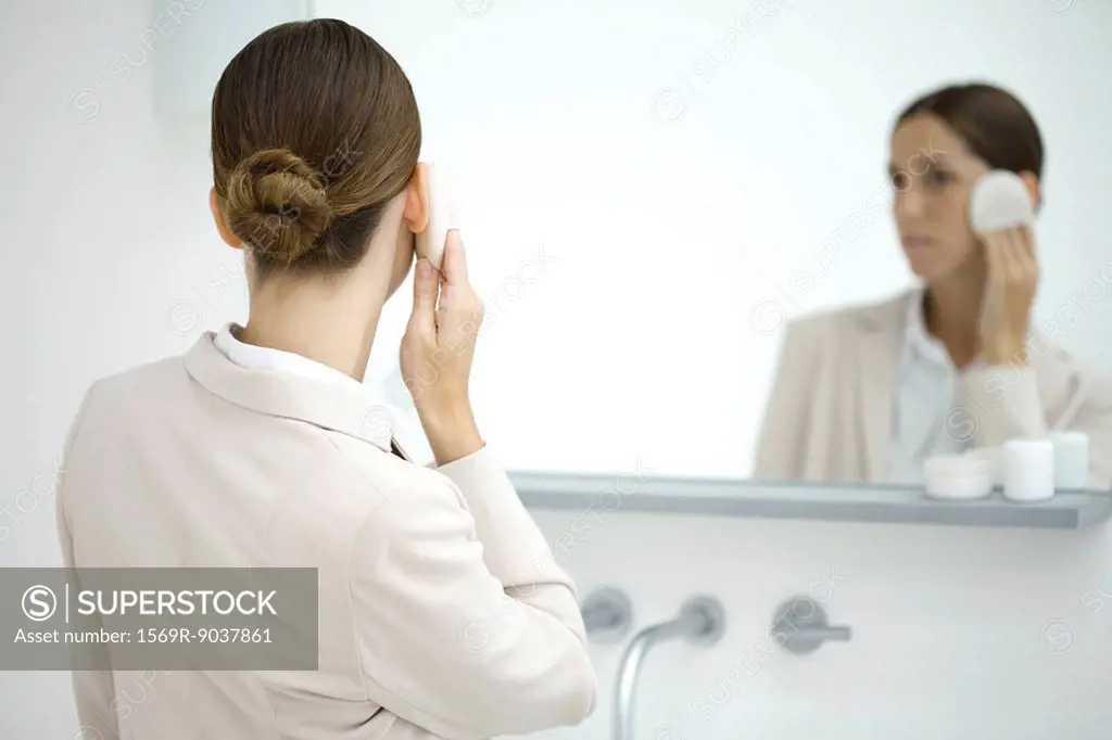 Professional woman powdering face in mirror, rear view