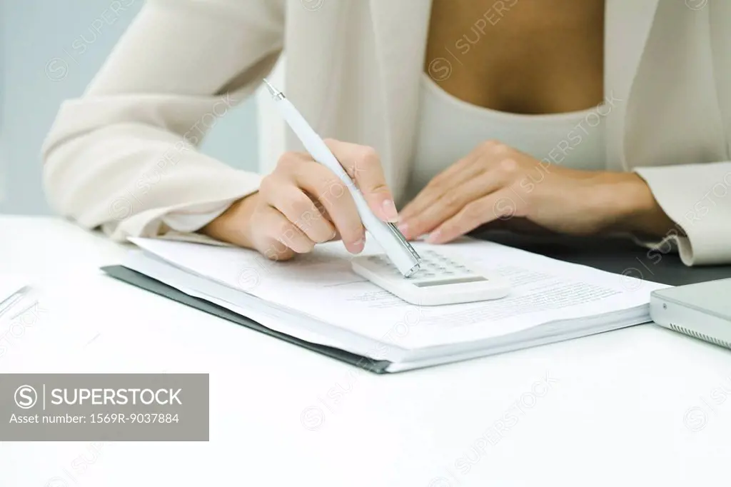 Professional woman using calculator, cropped view