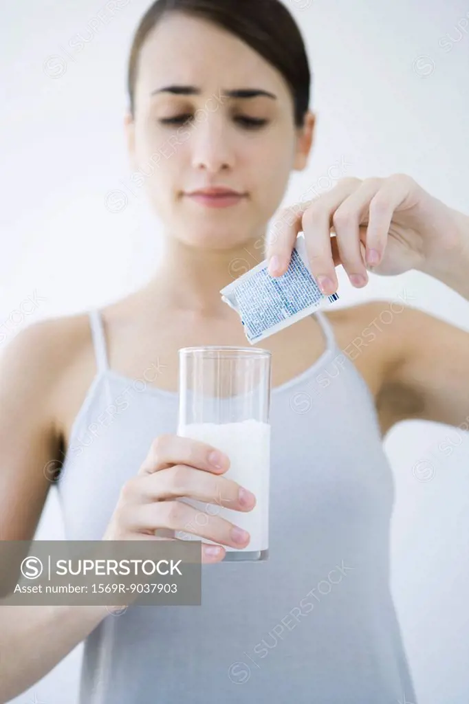 Woman pouring effervescent medicine into glass of water