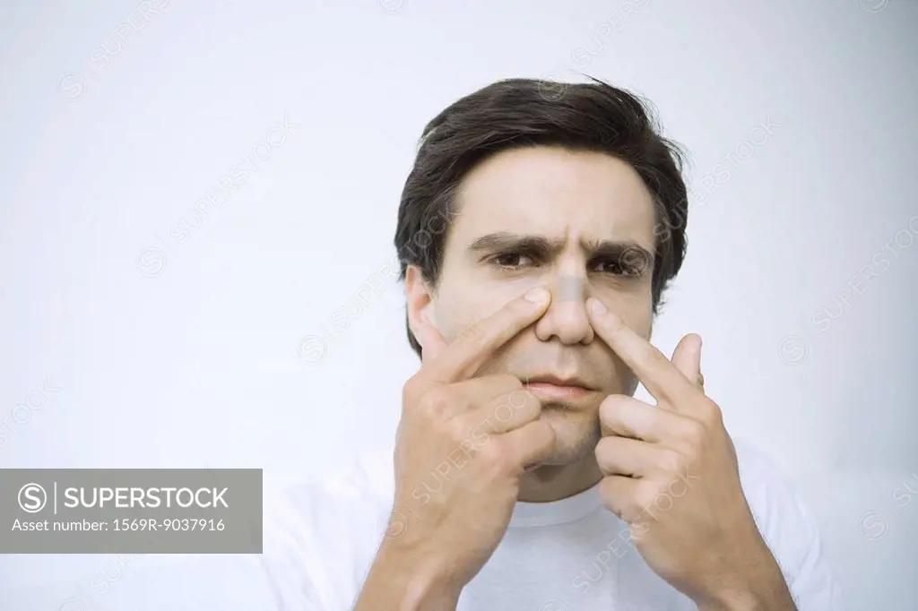 Man applying adhesive bandage on his nose, looking at camera