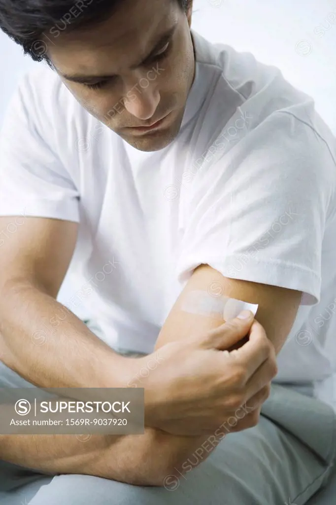 Man putting adhesive bandage on his arm