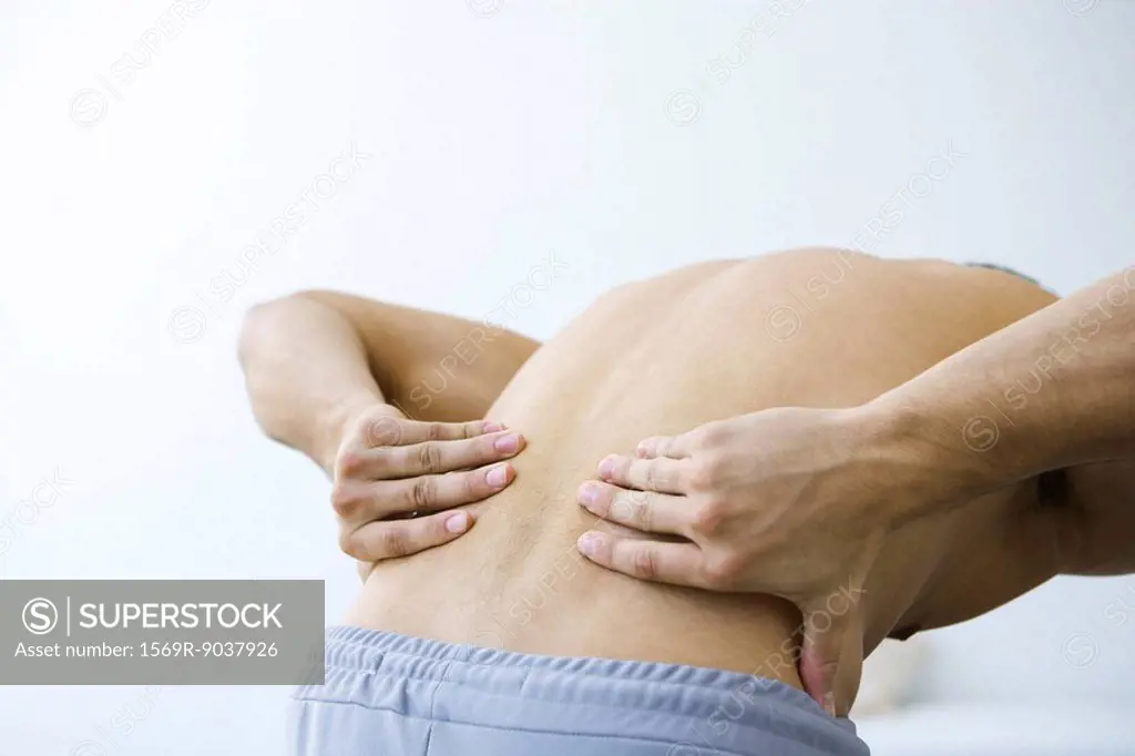 Man bending over, holding lower back, cropped view
