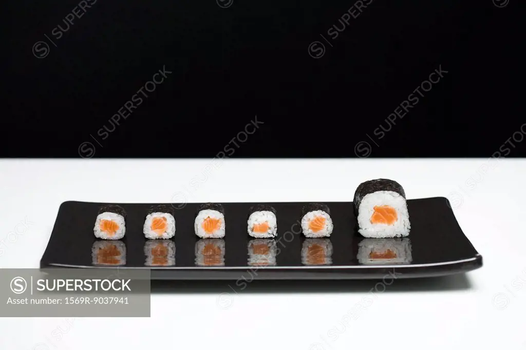 Maki sushi arranged on plate, one piece larger than the rest