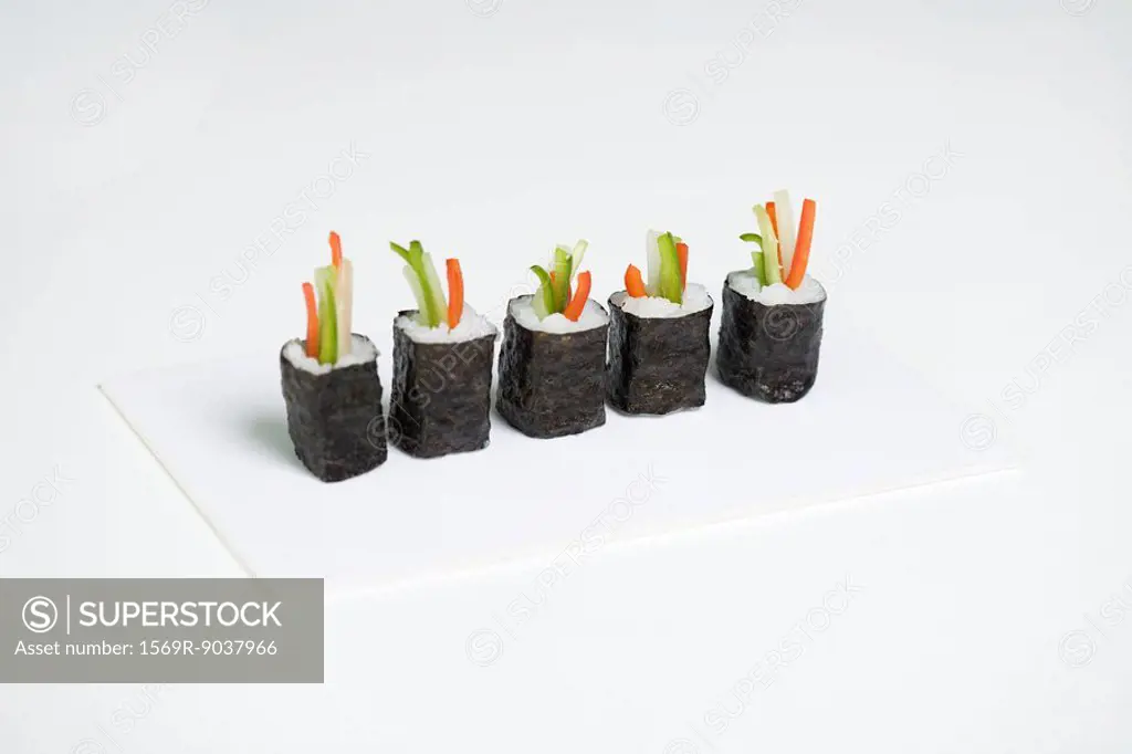Row of maki sushi arranged in row on cutting board