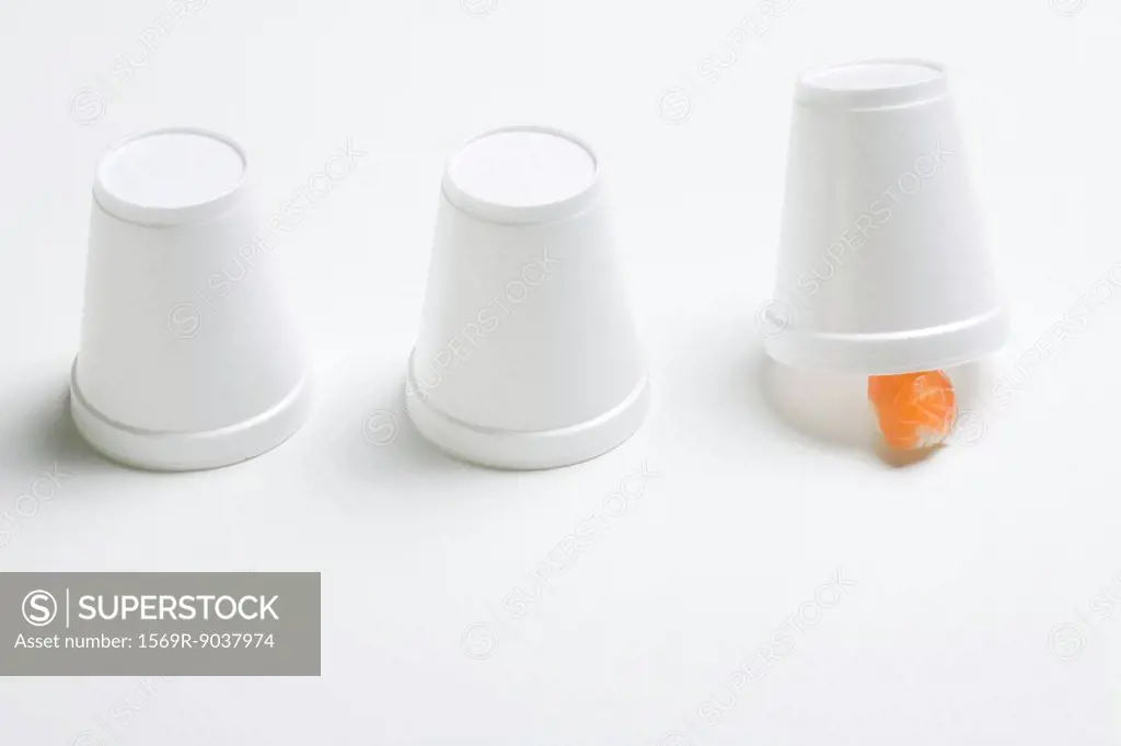 Three disposable cups in row, end cup lifted revealing single piece of nigiri sushi