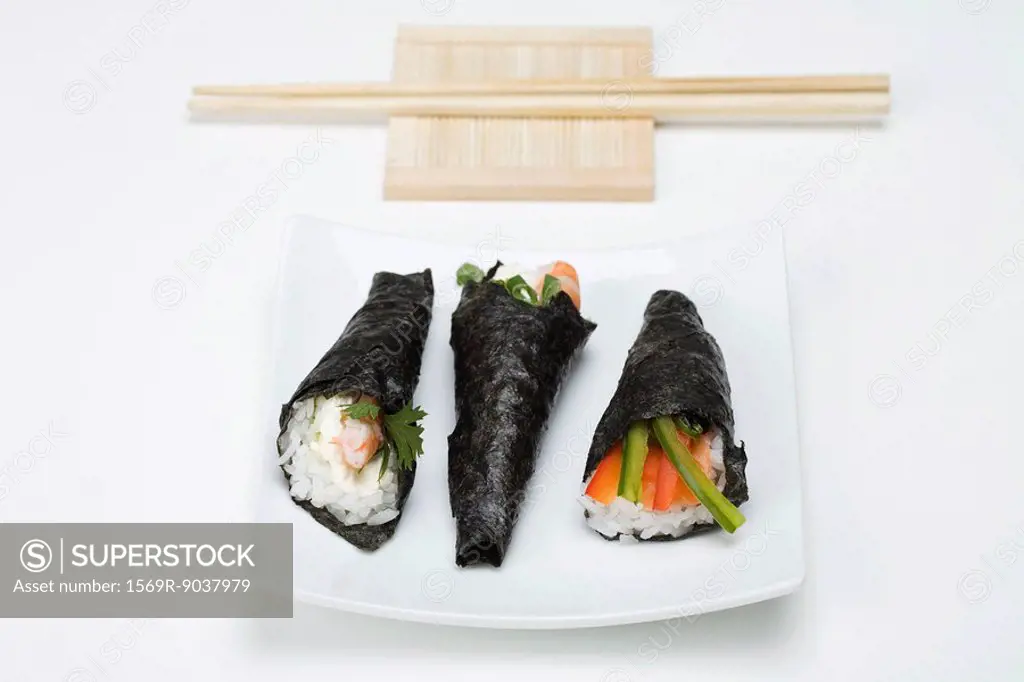 Temaki sushi on sushi plate with chopsticks