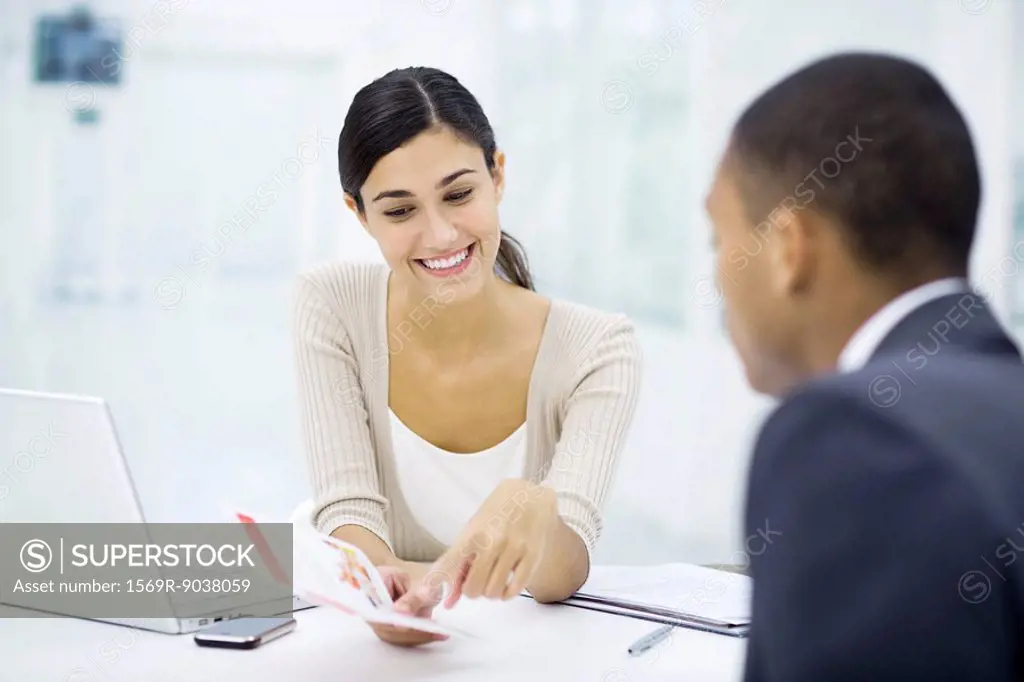 Professional woman reviewing brochure with customer