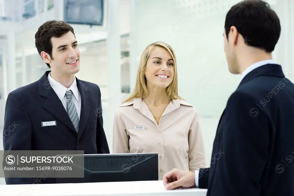 Customer service representatives smiling at businessman waiting at counter