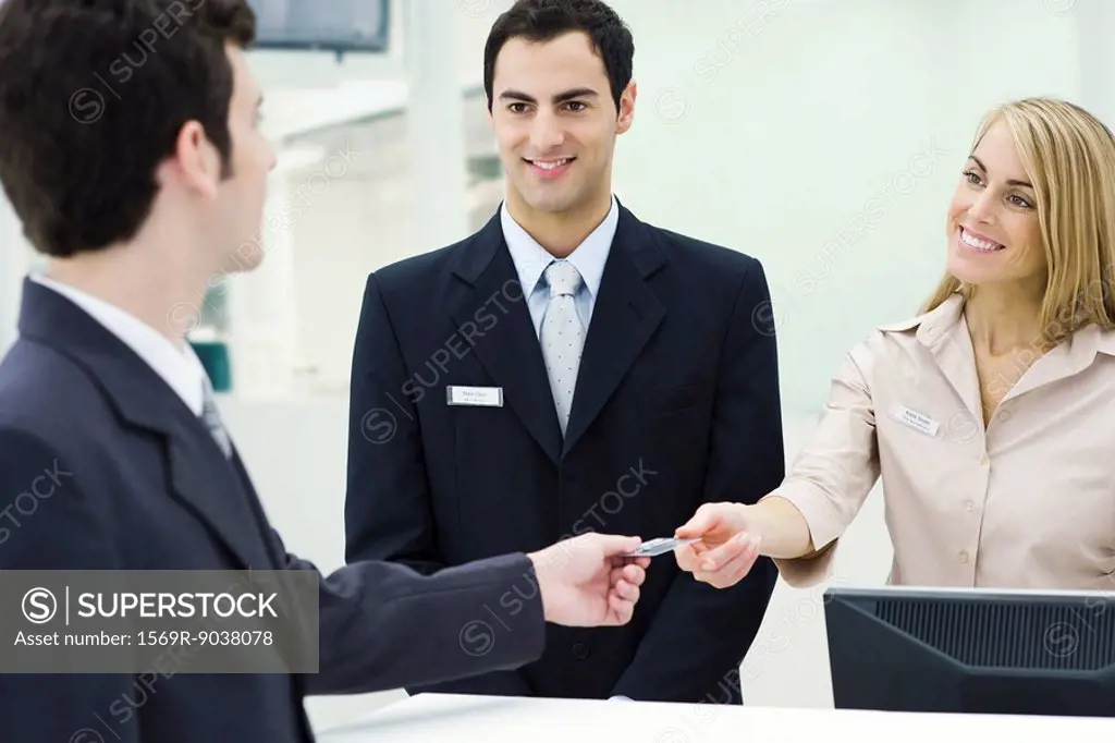 Man giving credit card to smiling customer service representatives