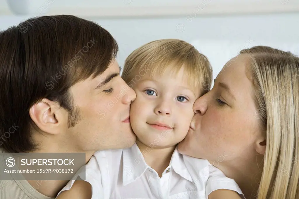 Parents kissing little boy´s cheeks, boy smiling at camera