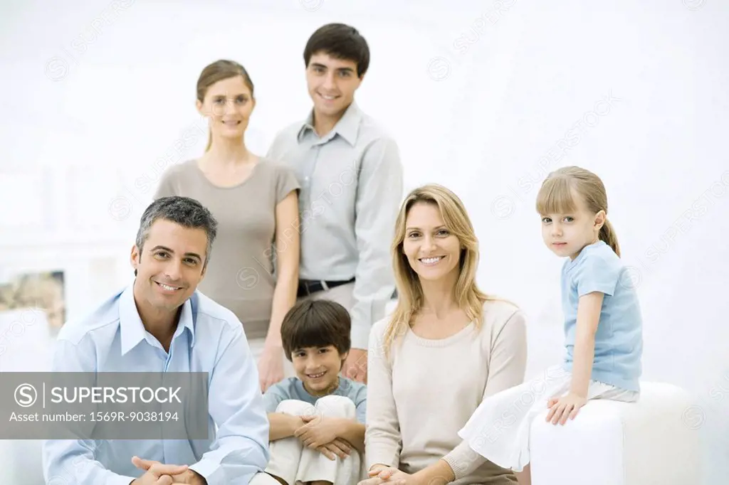 Family gathered around sofa, smiling at camera, group portrait