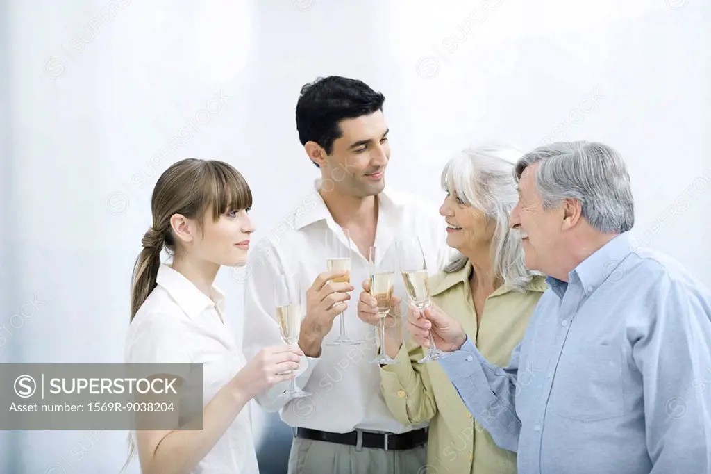 Couple standing with senior parents, all holding champagne flutes