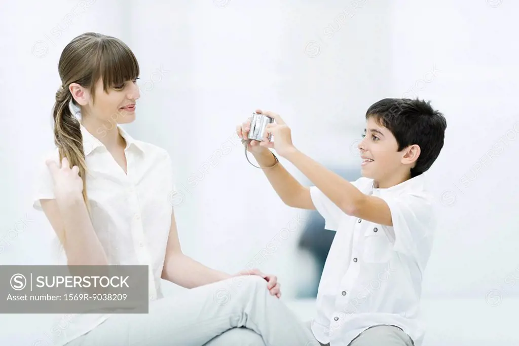Boy taking photo of young woman, side view