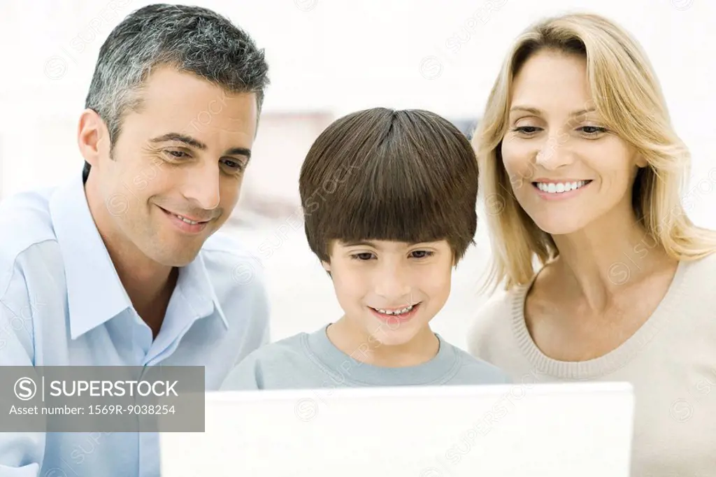 Family using laptop computer together, smiling