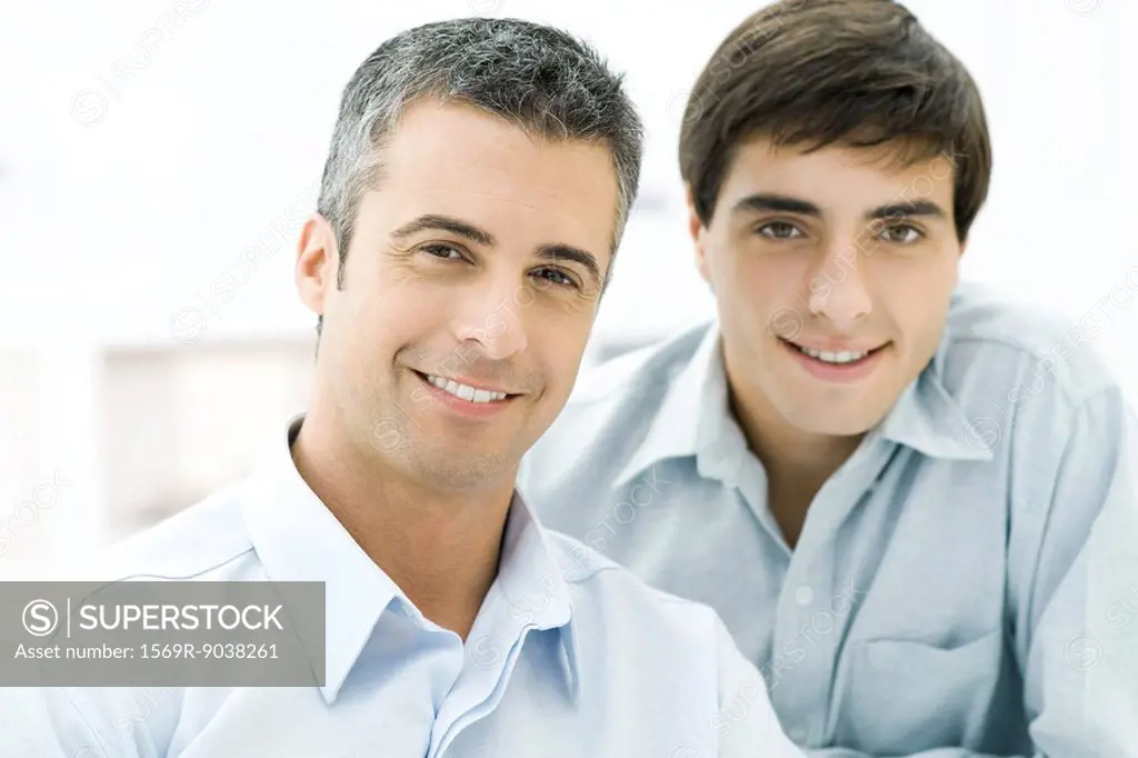 Father and adult son smiling at camera, portrait