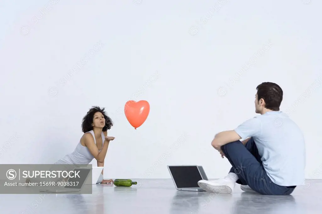Man and woman playing spin the bottle with laptop computers