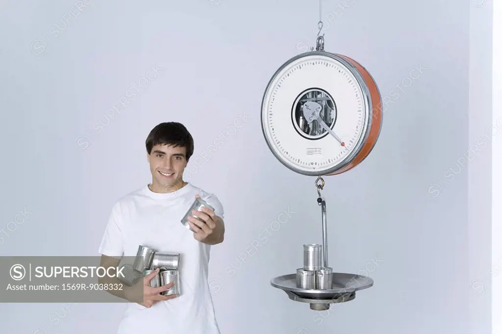 Man weighing cans on scale, offering one can to the camera