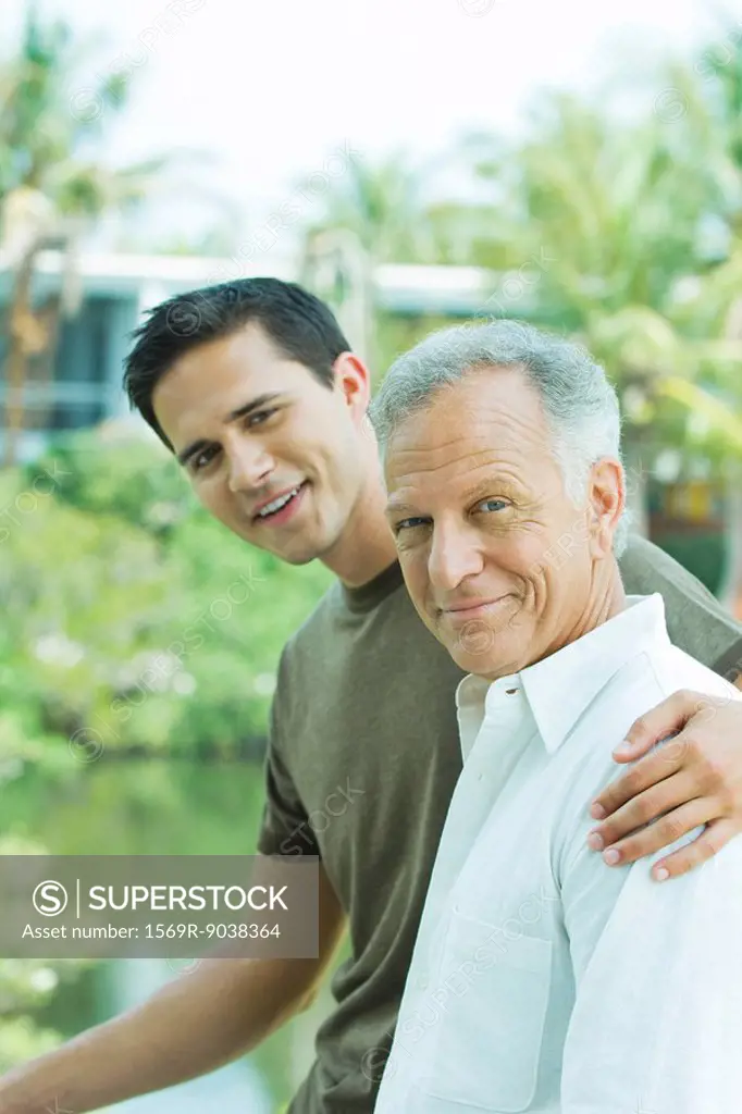 Young man with arm around father´s shoulder, both smiling, portrait