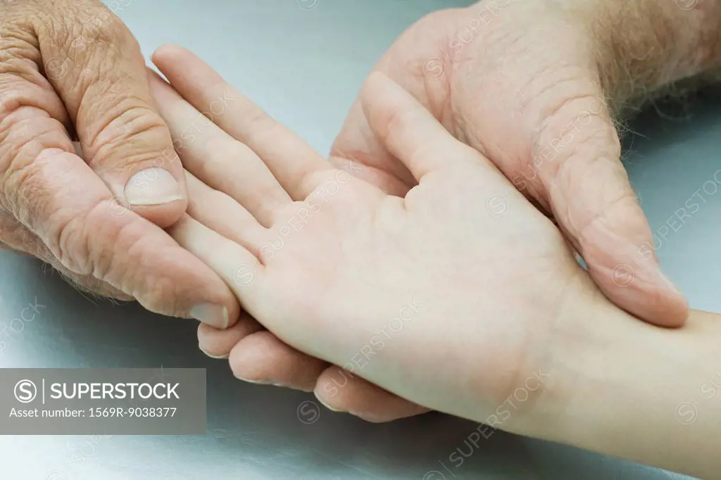Man holding young person´s hand, palm facing up, cropped view