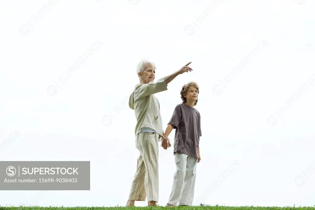 Grandmother walking hand in hand with grandson, pointing to the distance